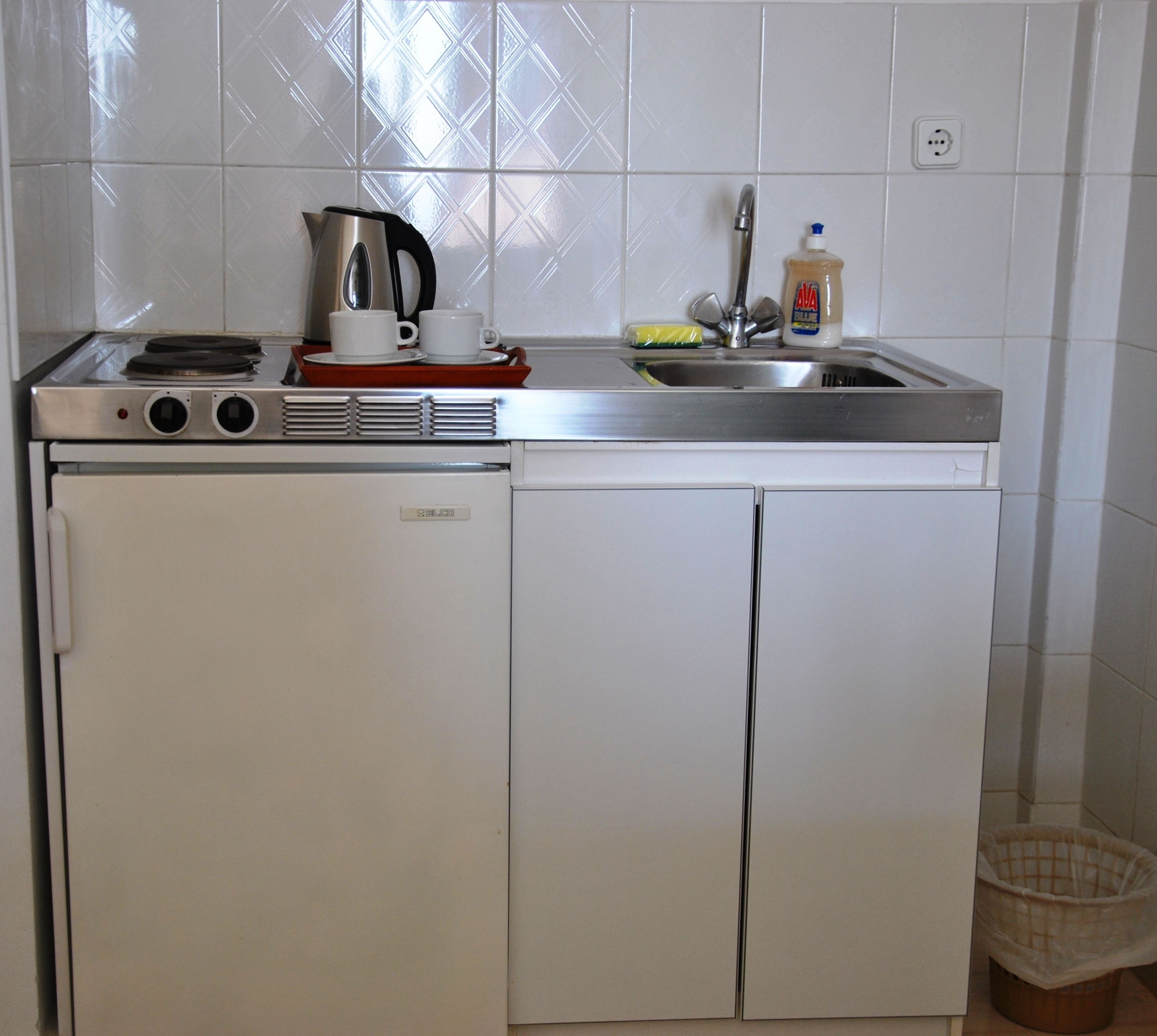 A compact kitchen with a refrigerator, a stove, and a sink.