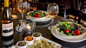 A restaurant with tables set for dining, featuring a bottle of wine, glasses, and a salad. - Flanigan's Resort and Spa (Springdale)
