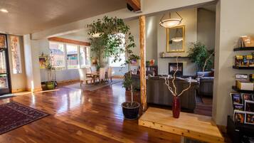 A spacious living area with hardwood flooring, a wooden coffee table, and several potted plants.