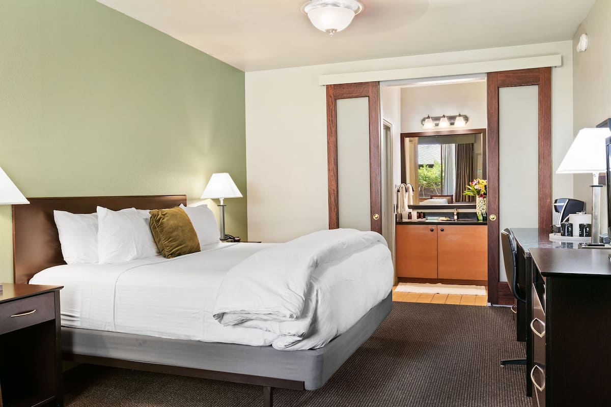 Een hotelkamer met een groot bed, nachtlampjes, een bureau en een spiegel.