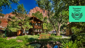 A lodge with a wooden deck, surrounded by lush greenery and a small pond with lily pads. - Flanigan's Resort and Spa (Springdale)