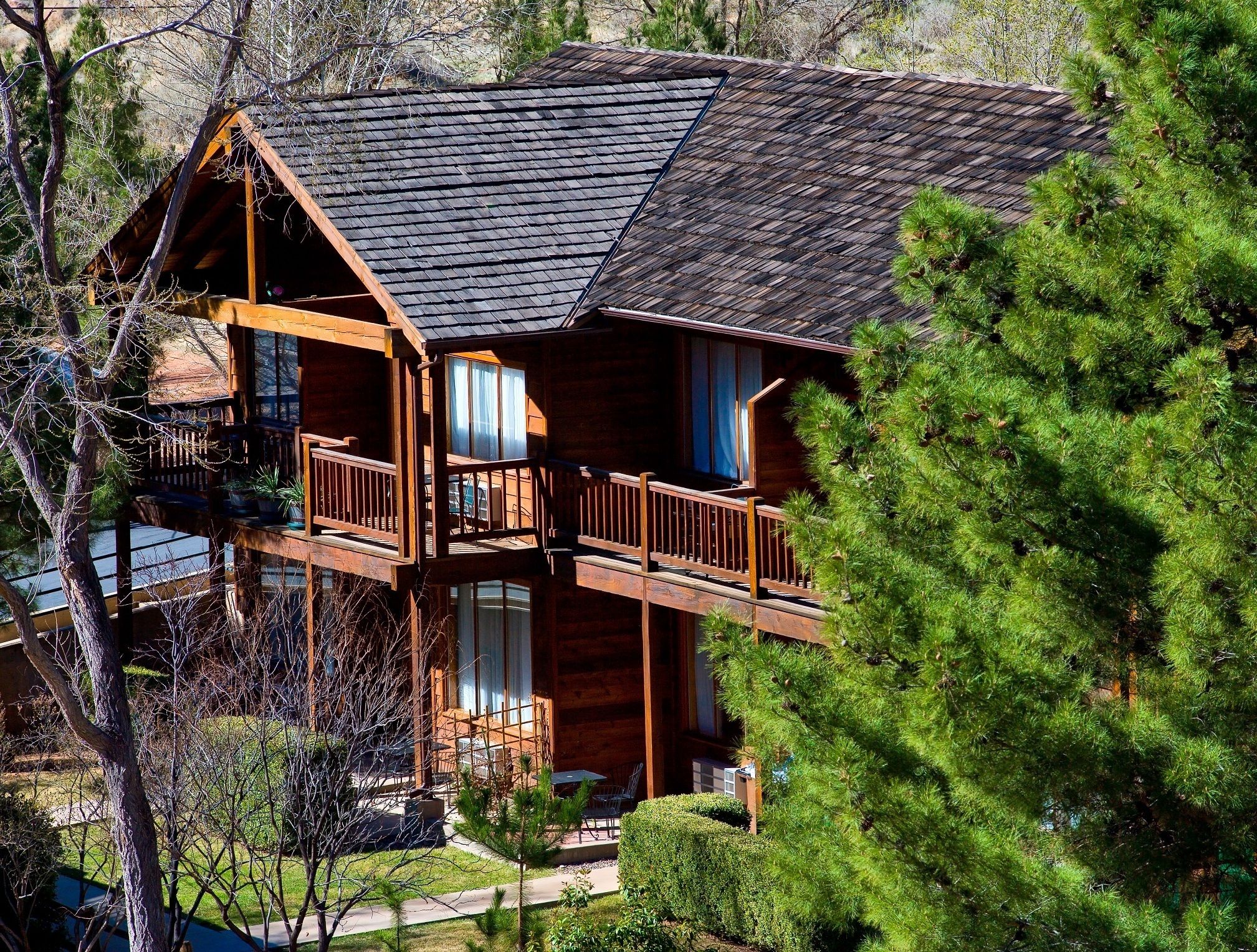 A two-story log cabin with a balcony, surrounded by greenery.