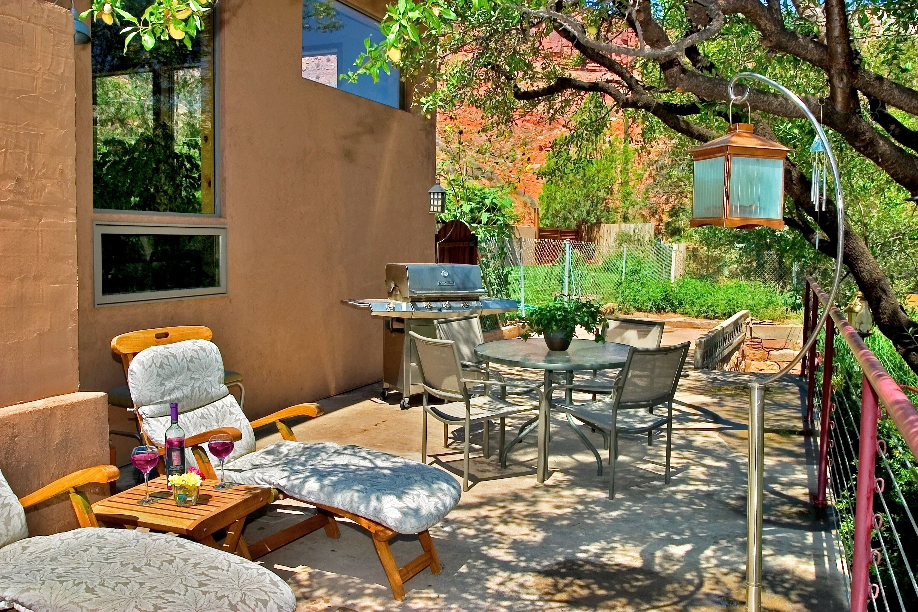 Een terras buiten met een barbecue, eettafel en stoelen.