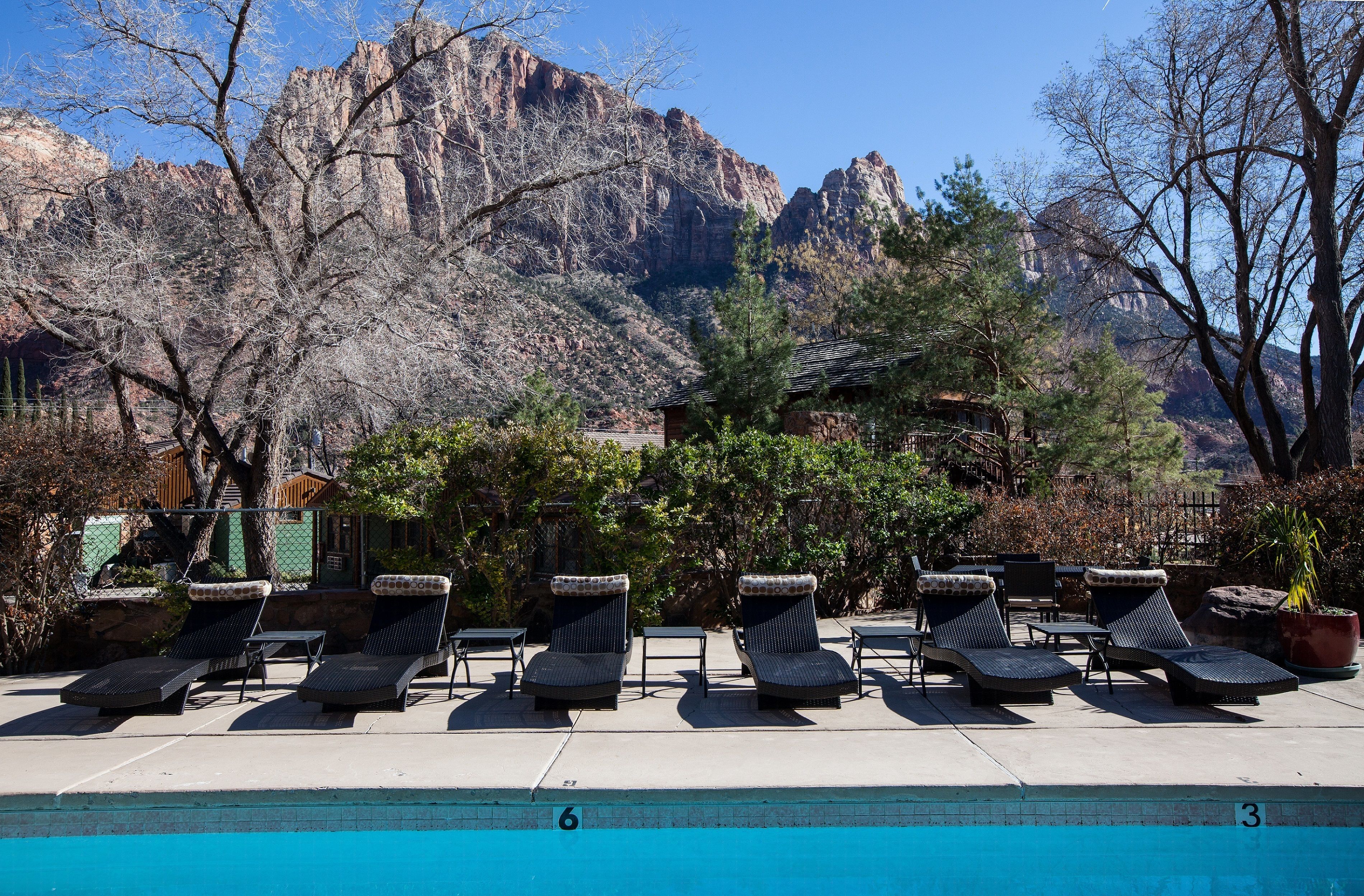 Un espace aménagé au bord de la piscine, avec des chaises longues et une vue sur un paysage montagneux.