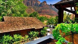 A wooden cabin with a sloped roof, surrounded by lush greenery and a mountain backdrop. - Flanigan's Resort and Spa (Springdale)
