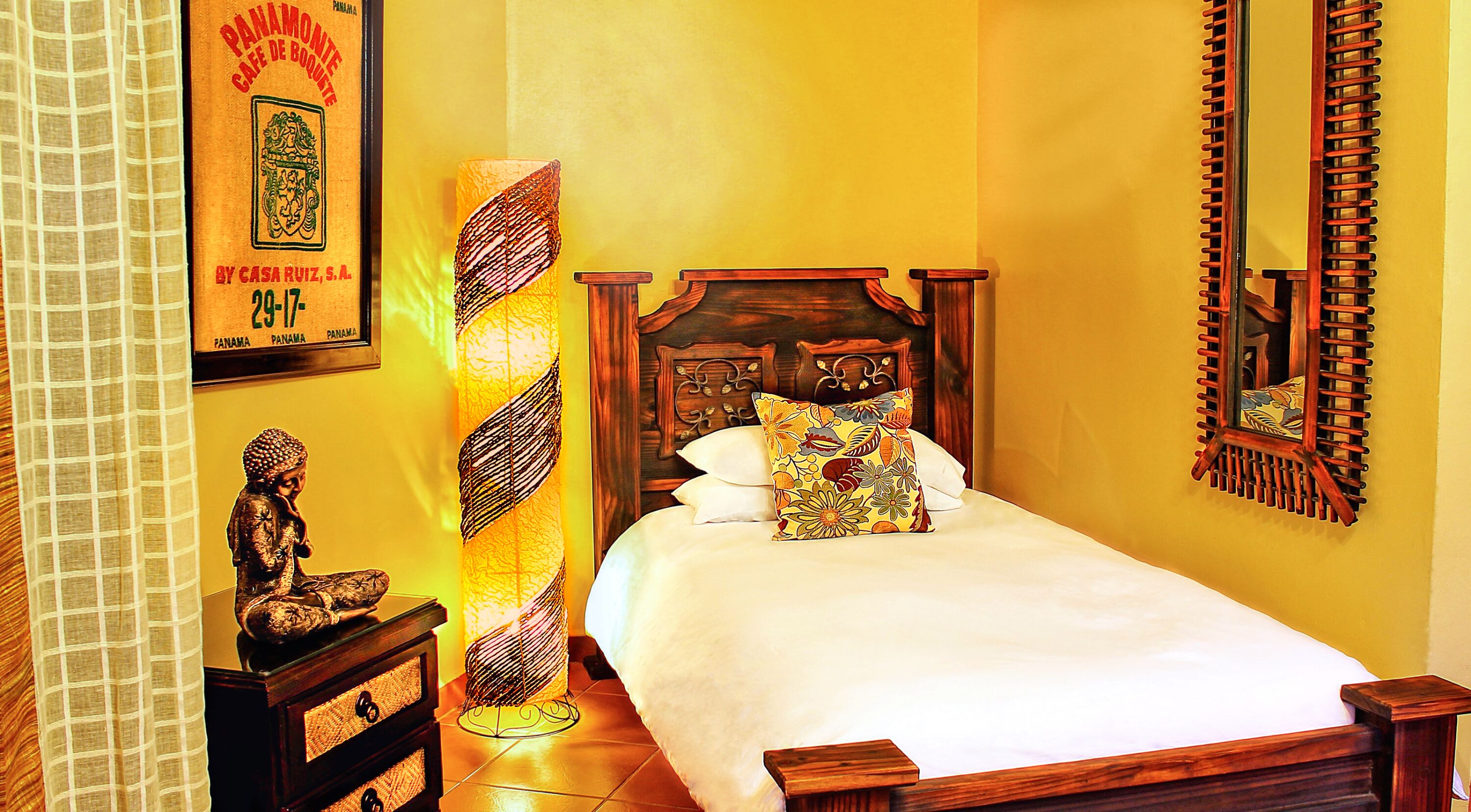 A bedroom with a wooden bed, a nightstand, a decorative lamp, and a framed picture on the wall.