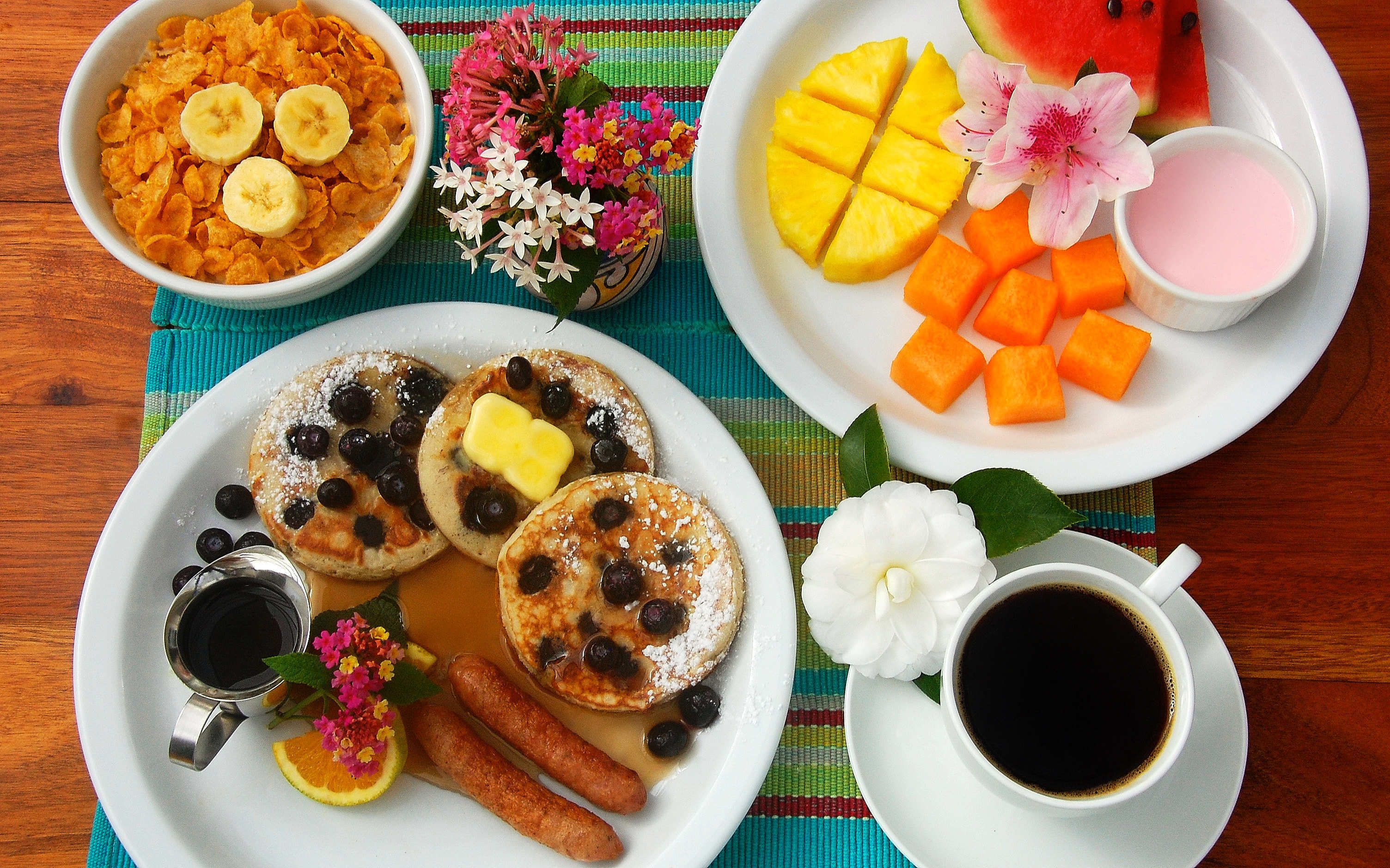 A breakfast setting with pancakes, fruit, and coffee.