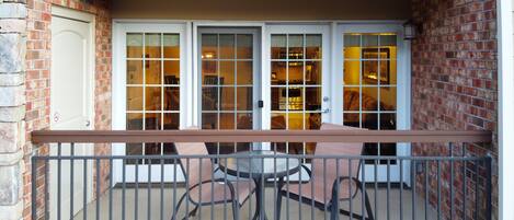 A balcony with a table and chairs, a brick wall, and a door with glass panels.