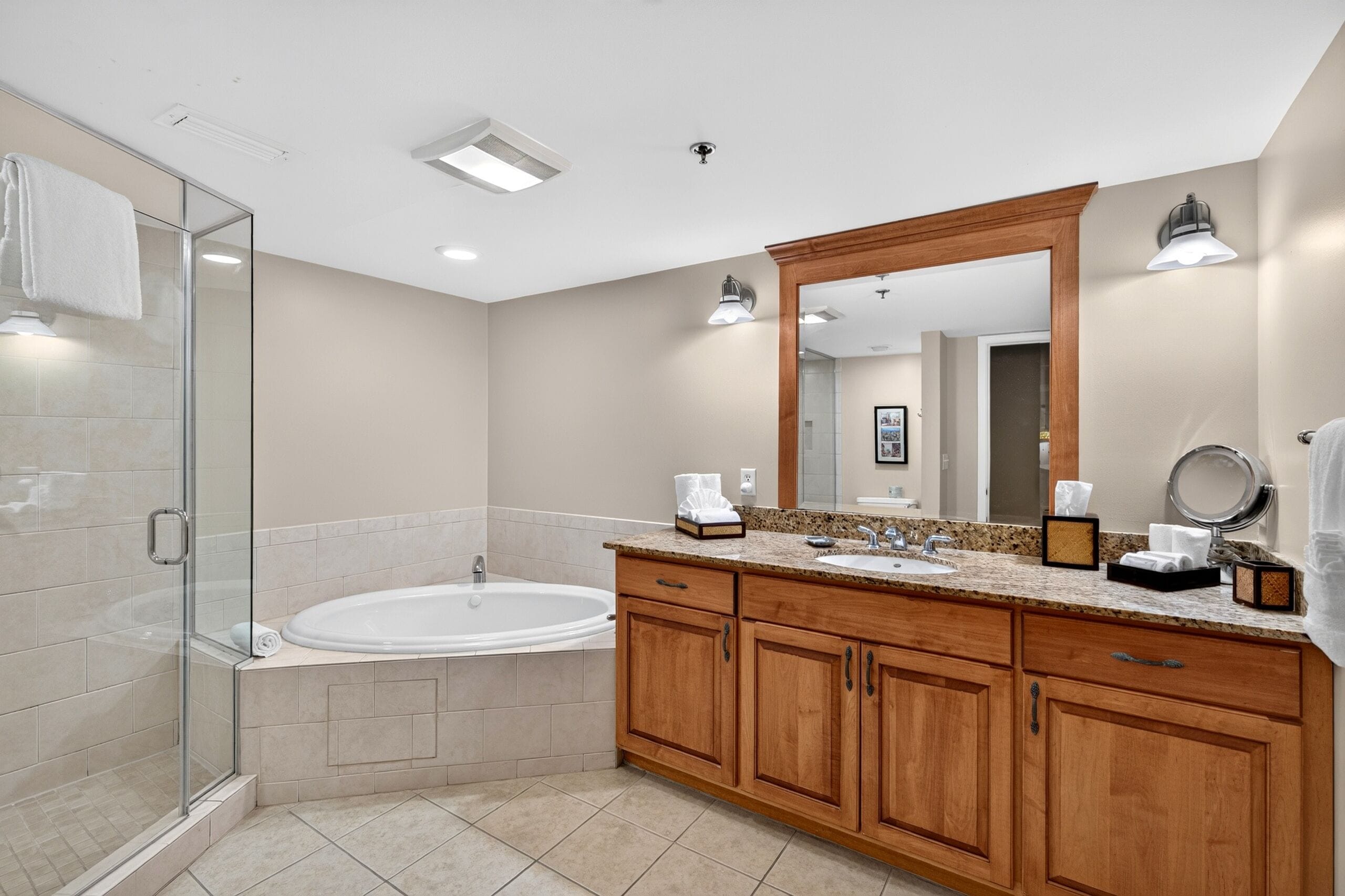 A modern bathroom with a glass shower enclosure, a freestanding bathtub, and wooden cabinetry.