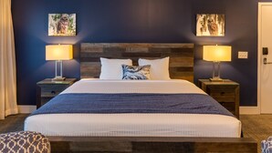 A neatly made bed with a wooden headboard, two bedside tables with lamps, and two wall-mounted artworks.