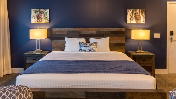 A neatly made bed with a wooden headboard, two bedside tables with lamps, and two wall-mounted artworks. - Lantern Lodge Asheville Biltmore Village (Asheville)