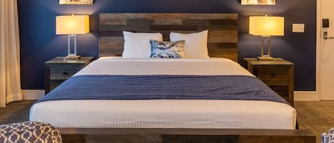 A neatly made bed with a wooden headboard, two bedside tables with lamps, and two wall-mounted artworks.