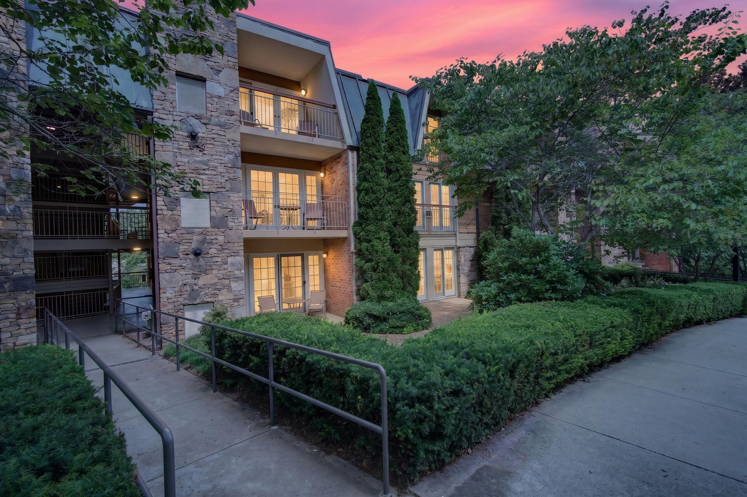 A multi-story building with balconies, stone facade, and a well-maintained garden.