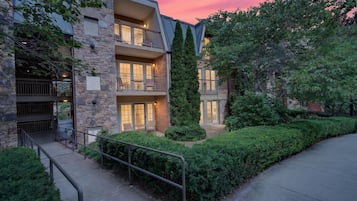 A multi-story building with balconies, stone facade, and a well-maintained garden.