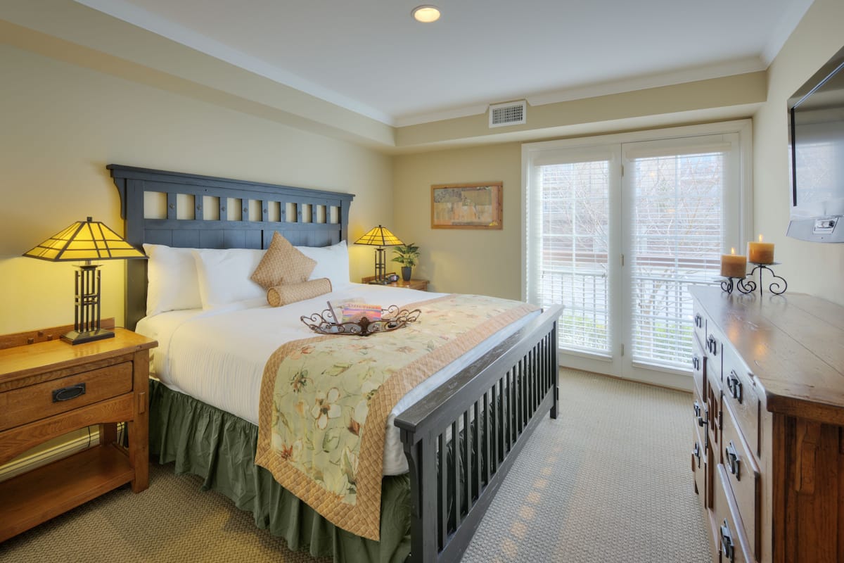 A bedroom with a bed, bedside tables, a dresser, and a window with blinds.
