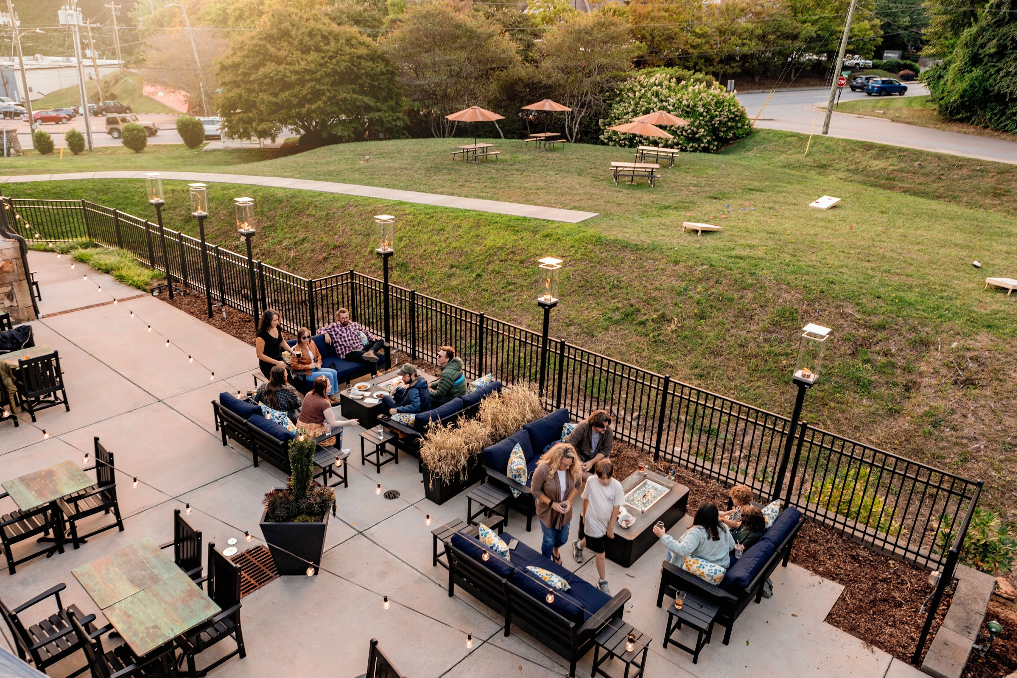 Un espace extérieur aménagé en patio, avec des sièges et des tables, le tout entouré d’une petite clôture.