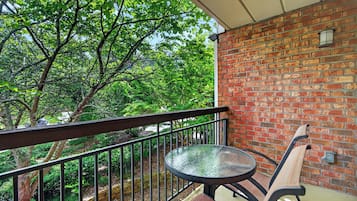 Un balcon avec un mur en briques, une rambarde en métal, une table ronde et un banc.