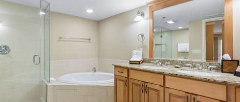 A modern bathroom with a glass shower enclosure, a freestanding bathtub, wooden cabinetry, and a large mirror.