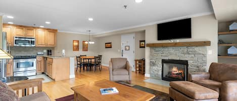 A spacious living area with a fireplace, a dining area, and a kitchen with modern appliances.