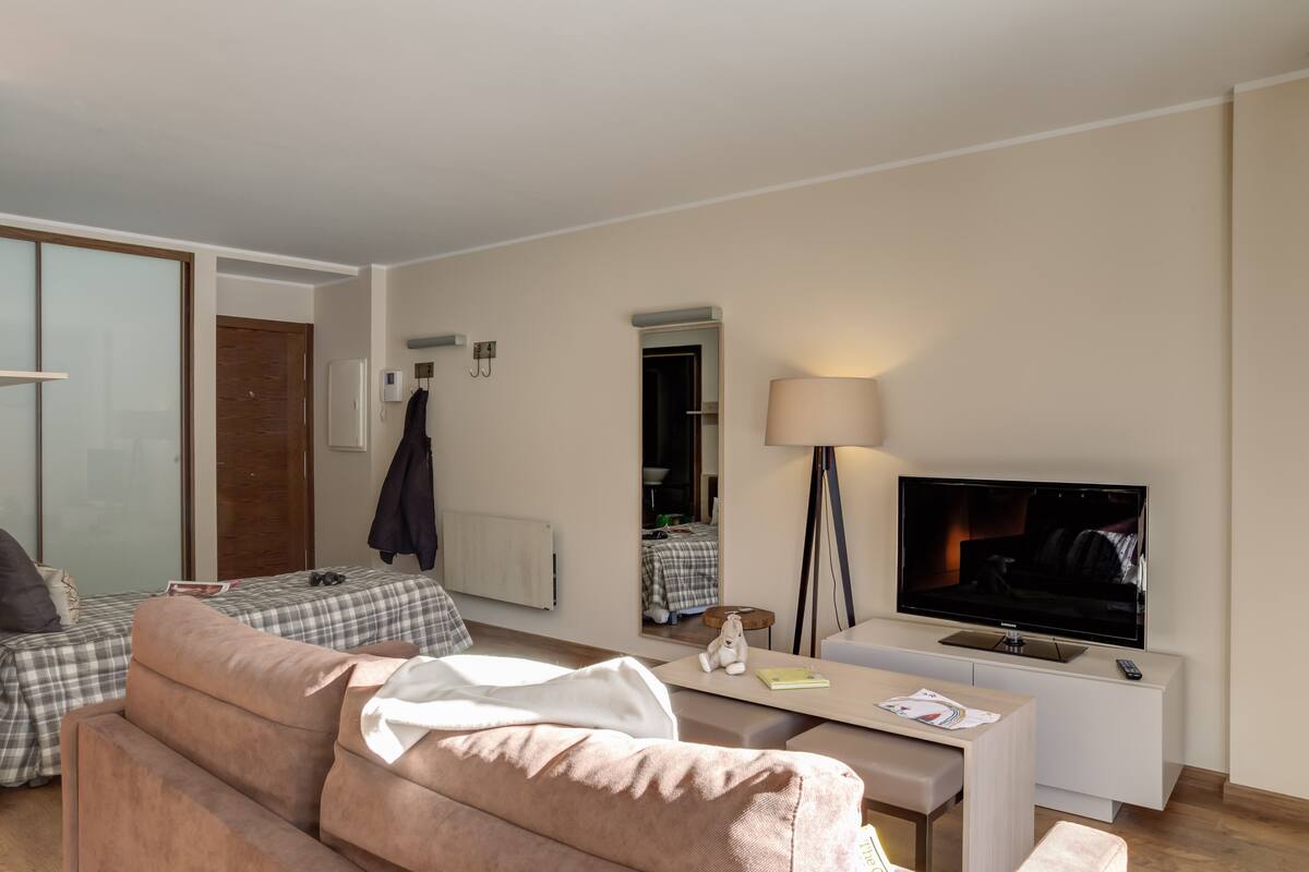Un salon moderne avec un canapé, une table basse, un téléviseur et une lampe.