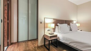 Une chambre d’hôtel avec un lit, des lampes de chevet, une table de chevet et un plancher en bois.