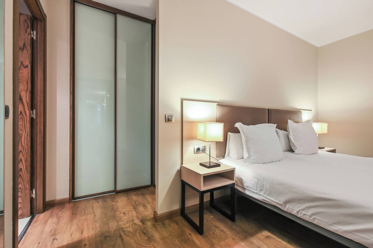 Une chambre d’hôtel avec un lit, des lampes de chevet, une table de chevet et un plancher en bois.