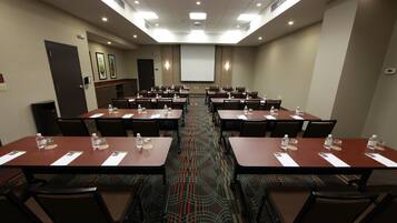 A conference room with multiple tables and chairs, equipped with water bottles and name cards.