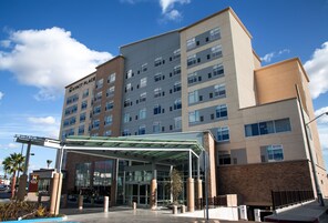 Un hotel de varios pisos con entrada de cristal y un área exterior cubierta.