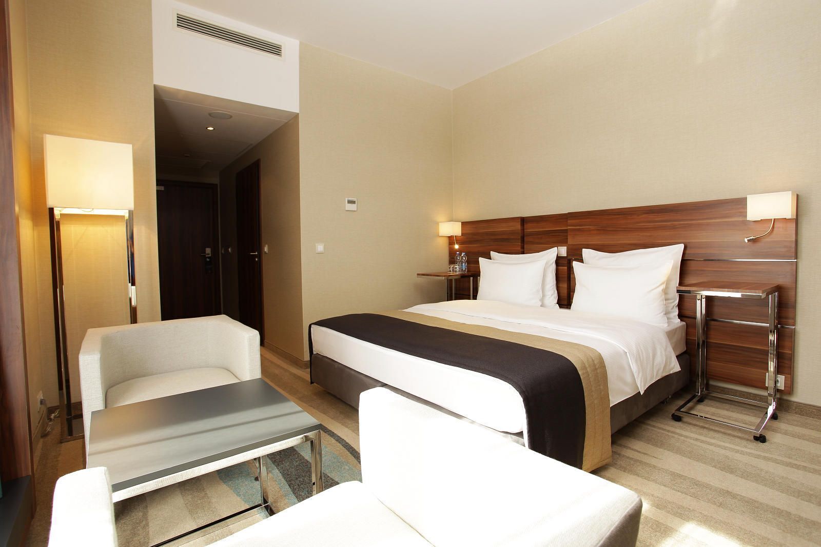 Una habitación de hotel con cama, mesitas de noche, una silla y un escritorio.