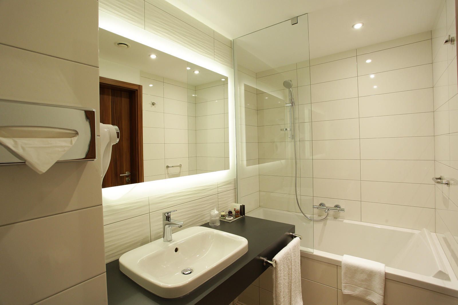 A modern bathroom with a large mirror, a sink, a shower, and a bathtub.