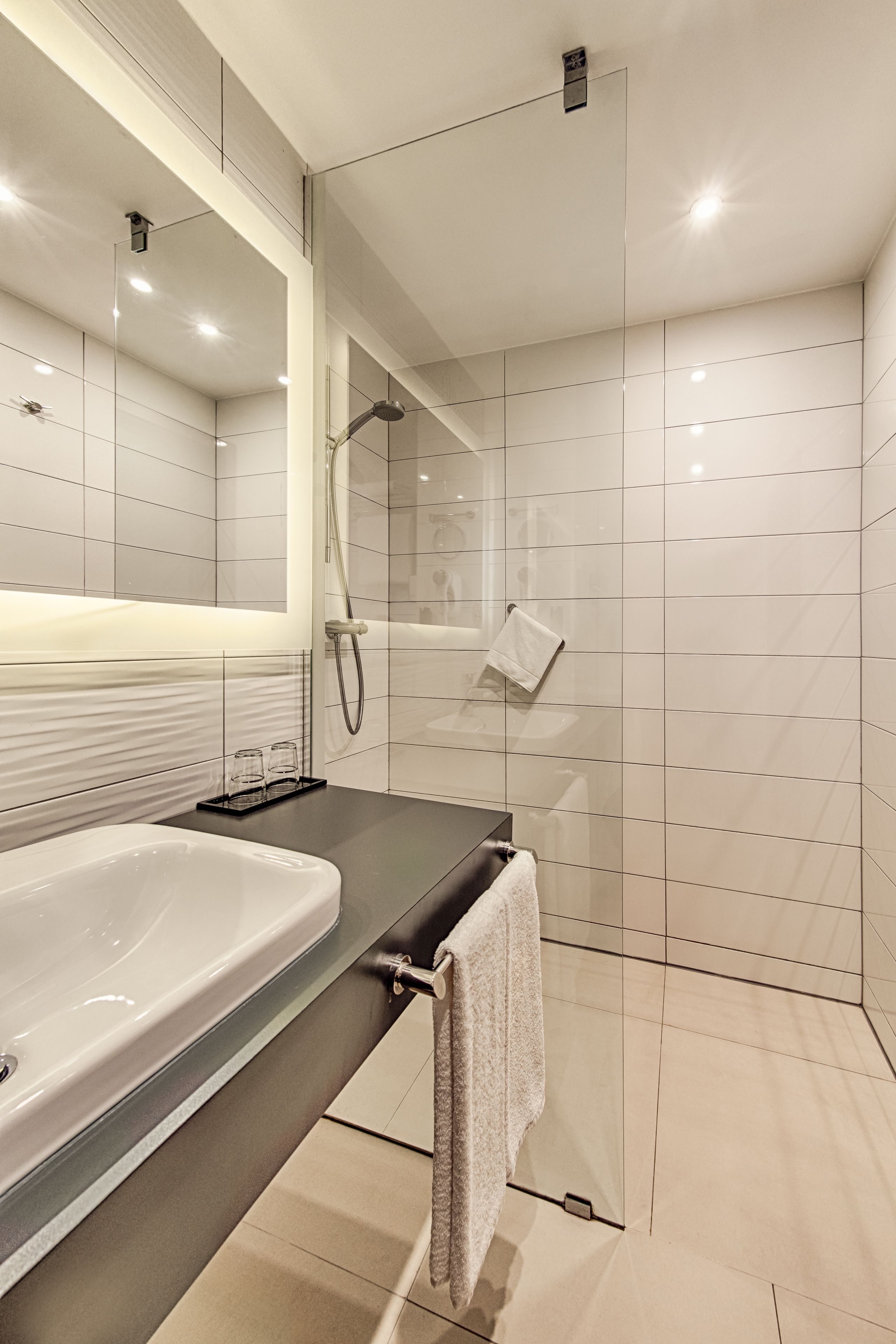 Ein modernes Badezimmer mit einer großen Badewanne, einer Duschkabine aus Glas und einem Handtuchhalter.