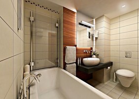Egy modern fürőszoba üveg válaszfallal ellátott zuhanyzóval, különálló fürdőkáddal, fa mosdóval és WC-vel.