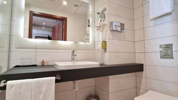 Un baño moderno con un espejo grande, un lavabo, un inodoro y un perchero para toallas.