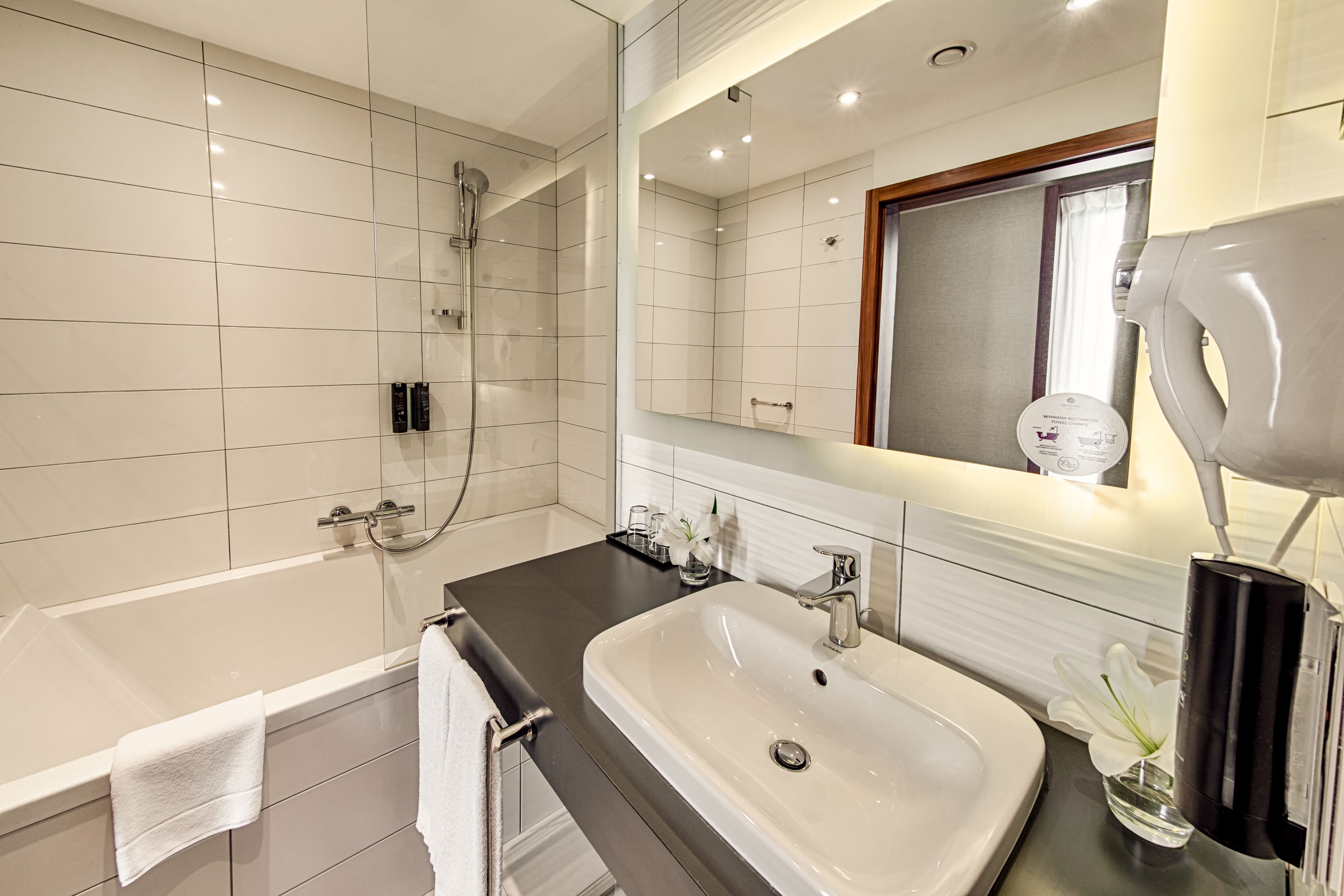A modern bathroom with a bathtub, a sink, a mirror, and a shower.