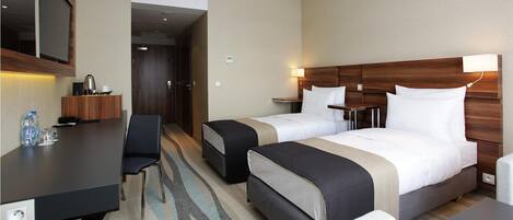 Une chambre d’hôtel avec deux lits, un bureau, une chaise et un mini-bar.