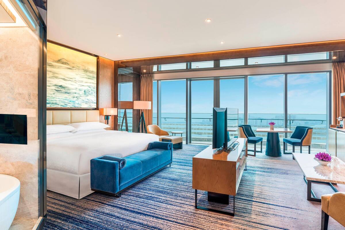 Ein modernes Hotelzimmer mit einem großen Bett, einem Schreibtisch und Blick aufs Meer.