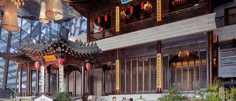 A traditional Chinese building with a modern glass extension, featuring a courtyard with seating and decorative lanterns.