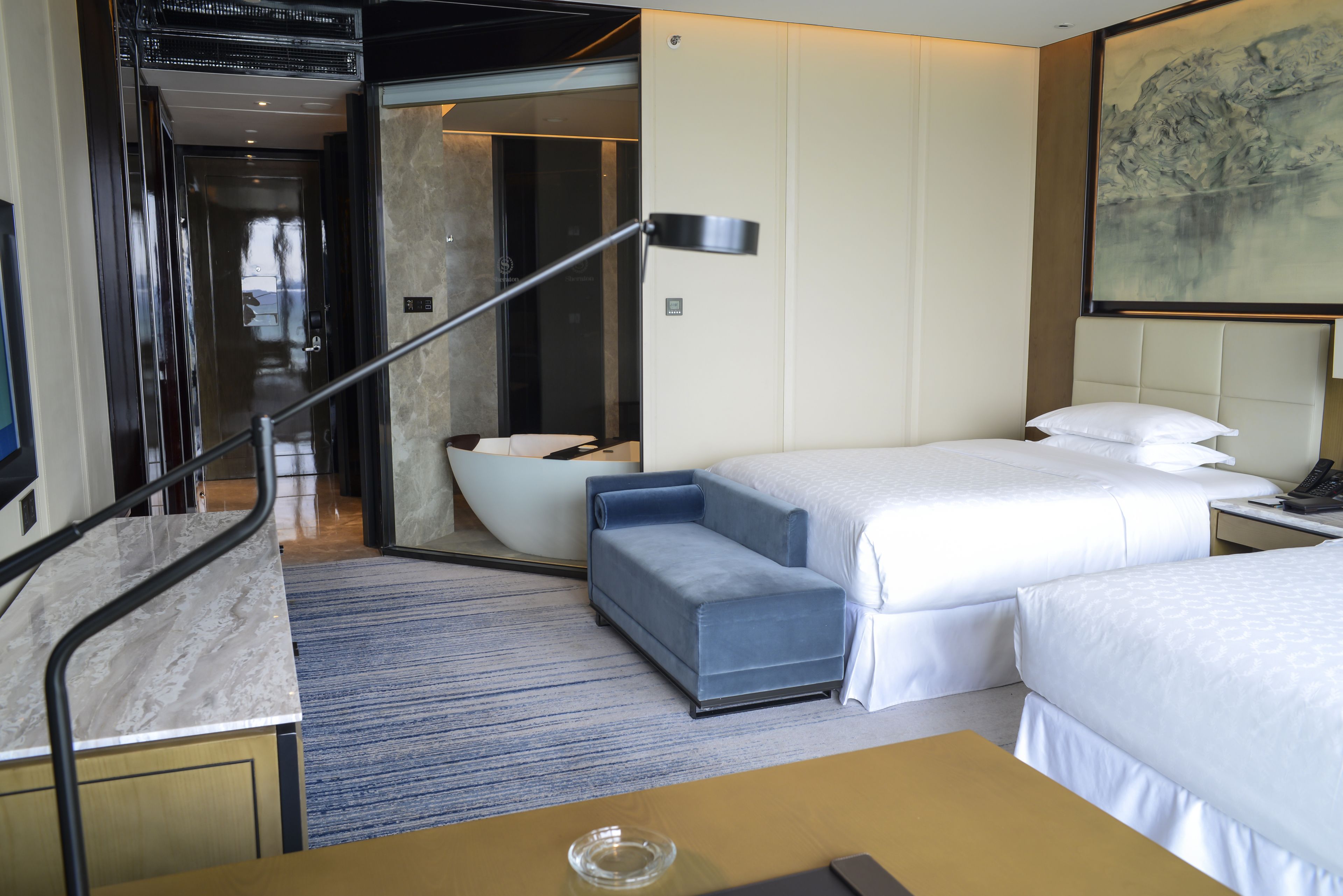 A hotel room with a bed, a desk, a chair, a bathroom, and a staircase.