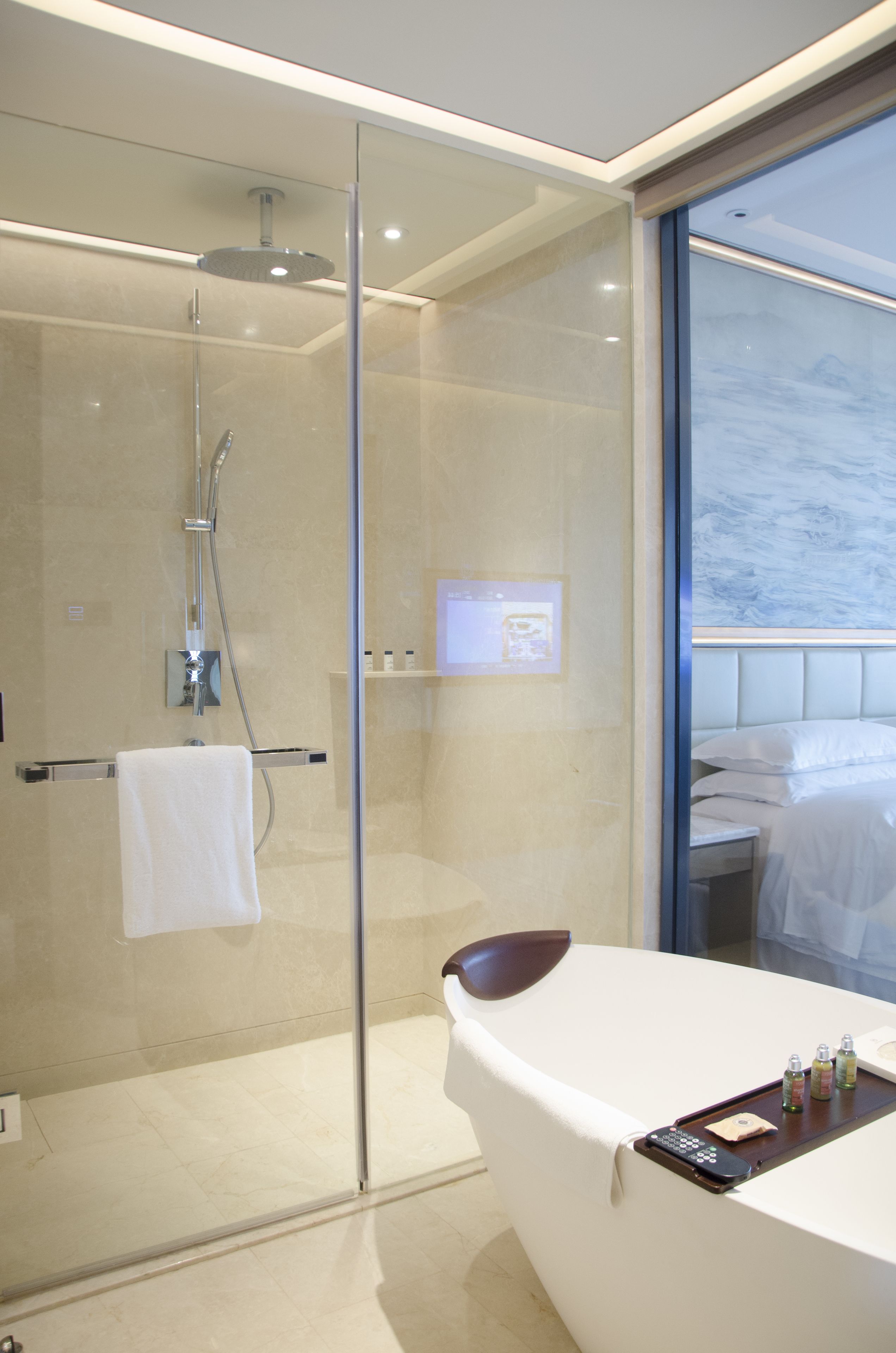 A modern bathroom with a glass-enclosed shower, a white bathtub, and a vanity with toiletries.