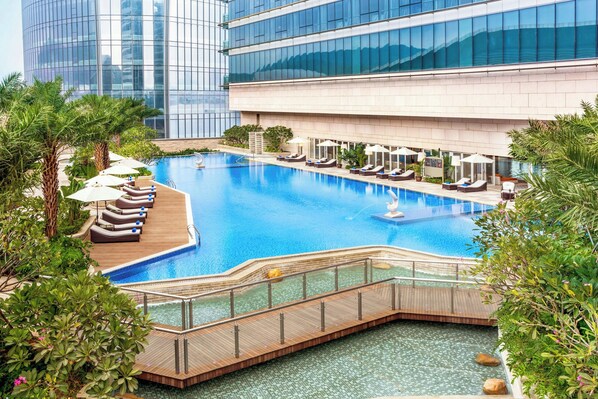 A modern hotel with a large indoor pool, sun loungers, and a wooden deck. - Sheraton Zhuhai Hotel (Zhuhai)