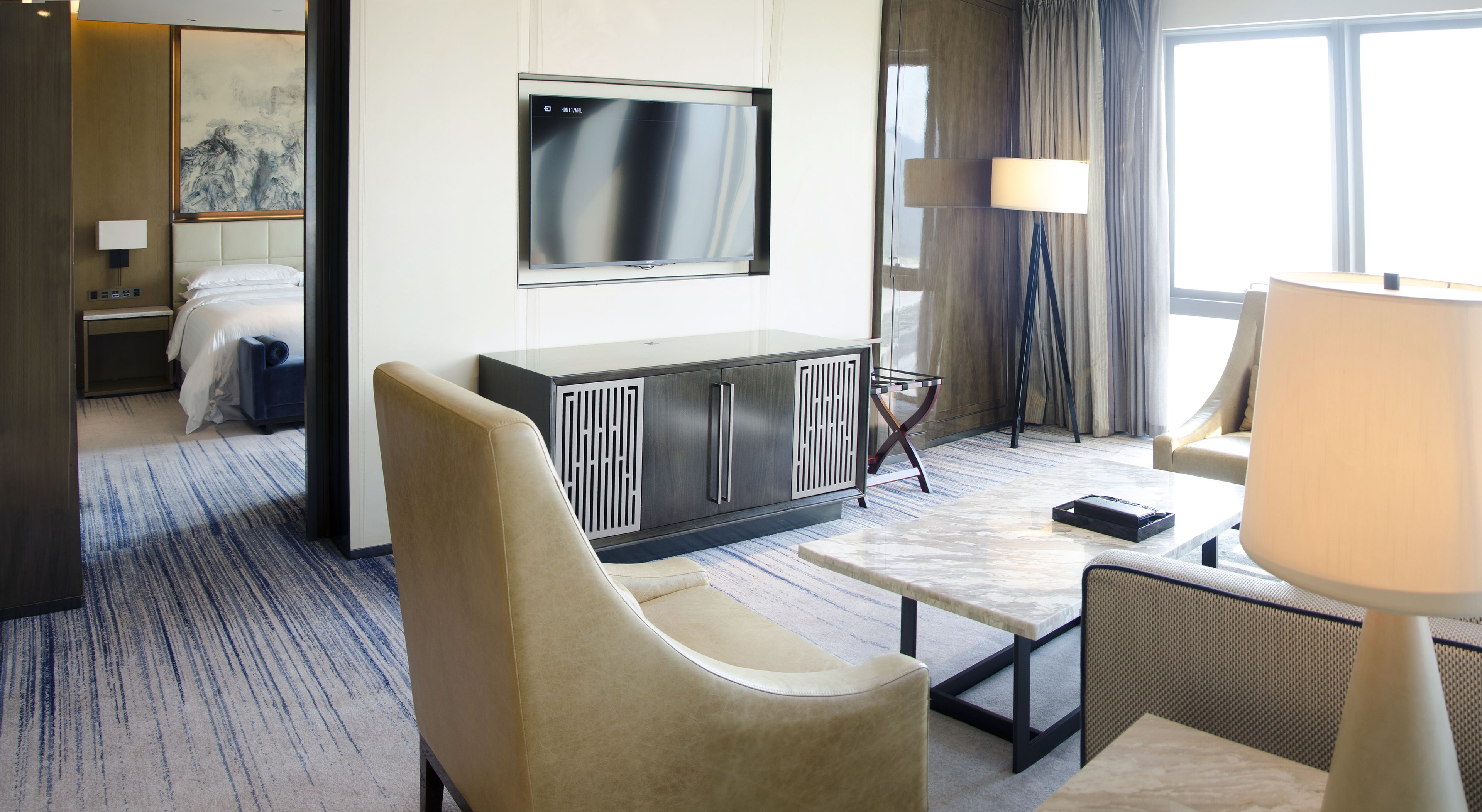 Een hotelkamer met een bed, een televisie, een bureau, een stoel en een lamp.