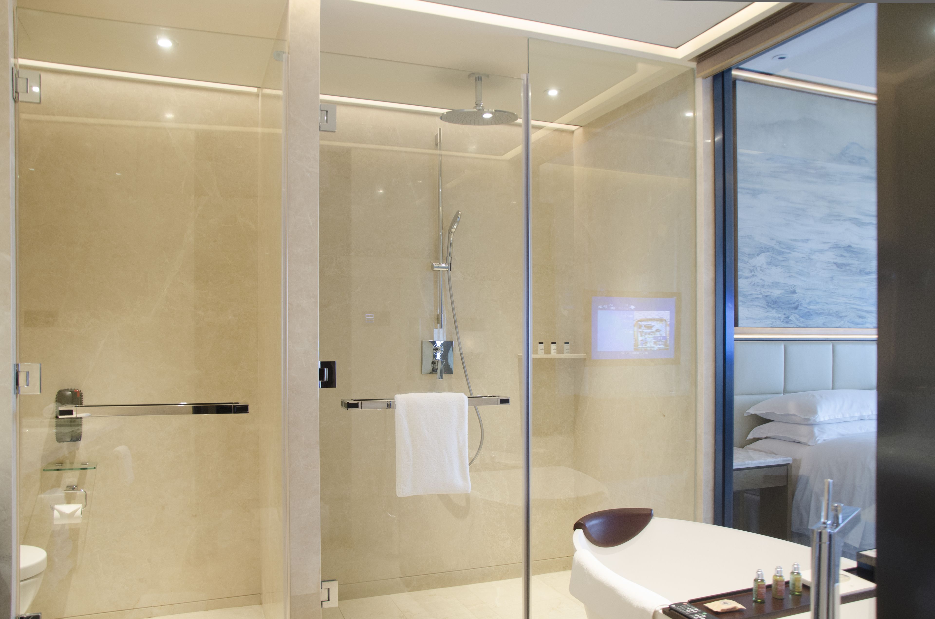 A modern bathroom with a glass-enclosed shower, a white bathtub, and a large window offering a view.