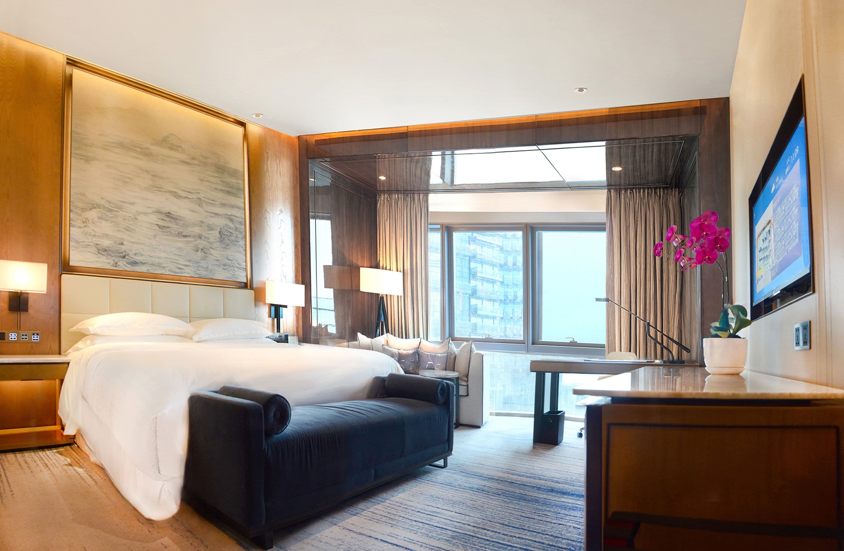 Una habitación de hotel con una cama grande, un sofá, un escritorio y una televisión.