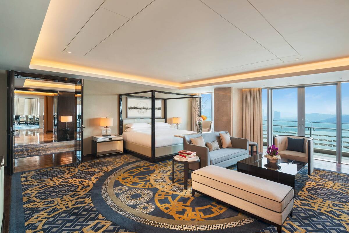 Ein modernes Hotelzimmer mit einem großen Bett, einer Couch, einem Couchtisch und Blick auf den Ozean.