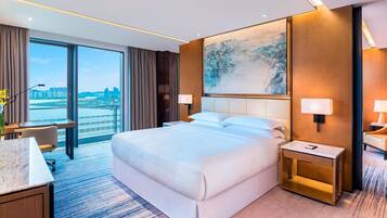 A modern hotel room with a large bed, a desk, and a view of the cityscape.