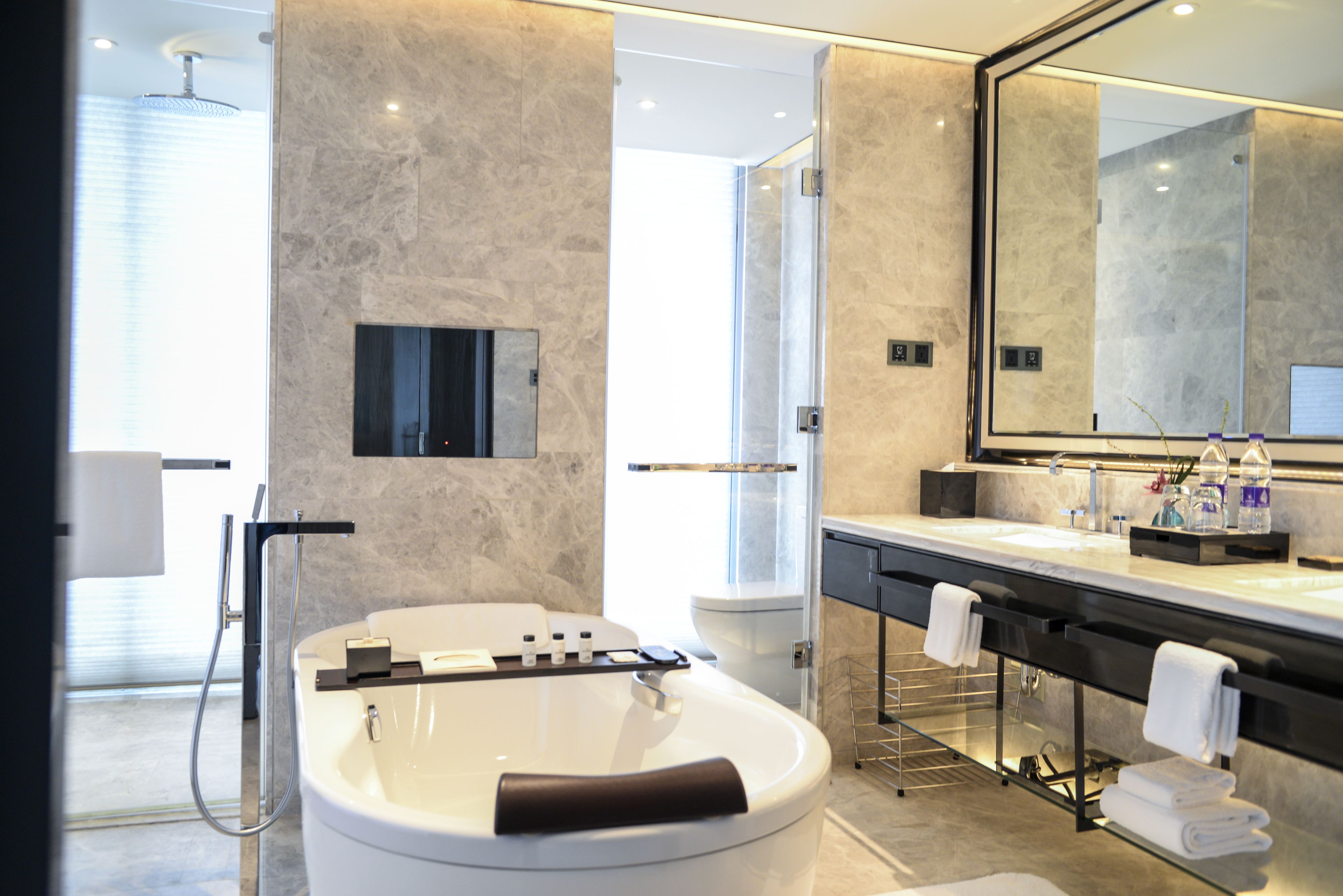 A modern bathroom with a freestanding bathtub, a large mirror, and a glass-enclosed shower.