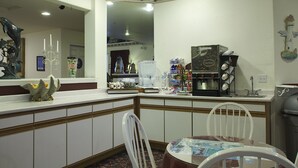 A corner kitchen with a white countertop, a coffee machine, and a refrigerator. - Lighthouse Inn (Crescent City)