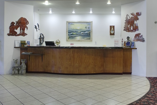 Una recepción con detalles de madera, un cuadro enmarco con una playa y figuras decorativas de animales.