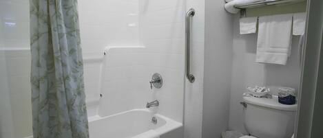 A bathroom with a bathtub, toilet, and shower curtain.
