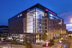 Un hôtel moderne, avec une façade en verre, de nombreux étages et une enseigne bien visible sur le toit.